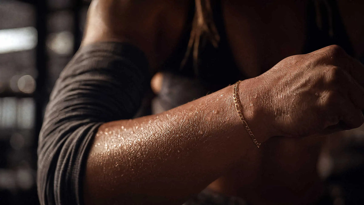 Nahaufnahme einer Frau beim Workout mit Kettlebell, die eine silberfarbene Edelstahl-Halskette mit Herzanhänger trägt. Zeigt die physische Belastung von Schmuck beim Sport durch Schweiss und mechanische Reibung.