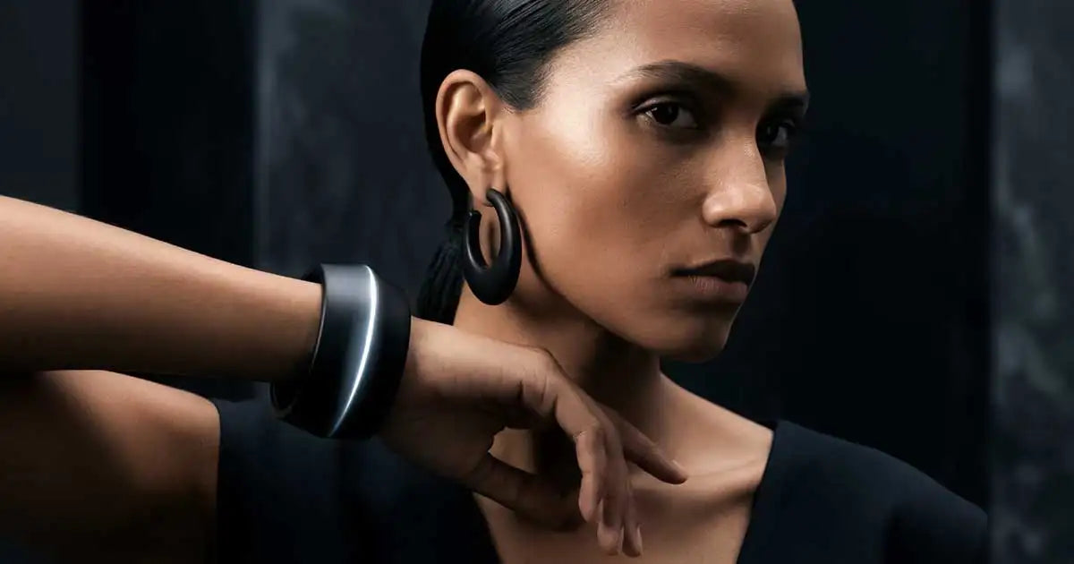 Dunkler Schmuck in Onyx-Optik und ein Layering-Armband auf dunklem Untergrund.